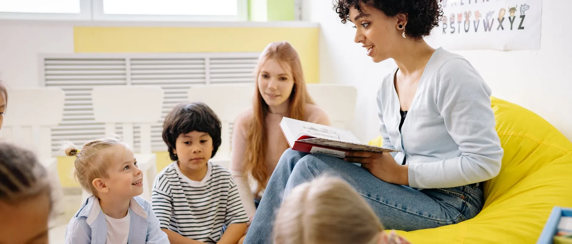 A Cedar Lane teacher reading to a small group of children in a bright Edison classroom